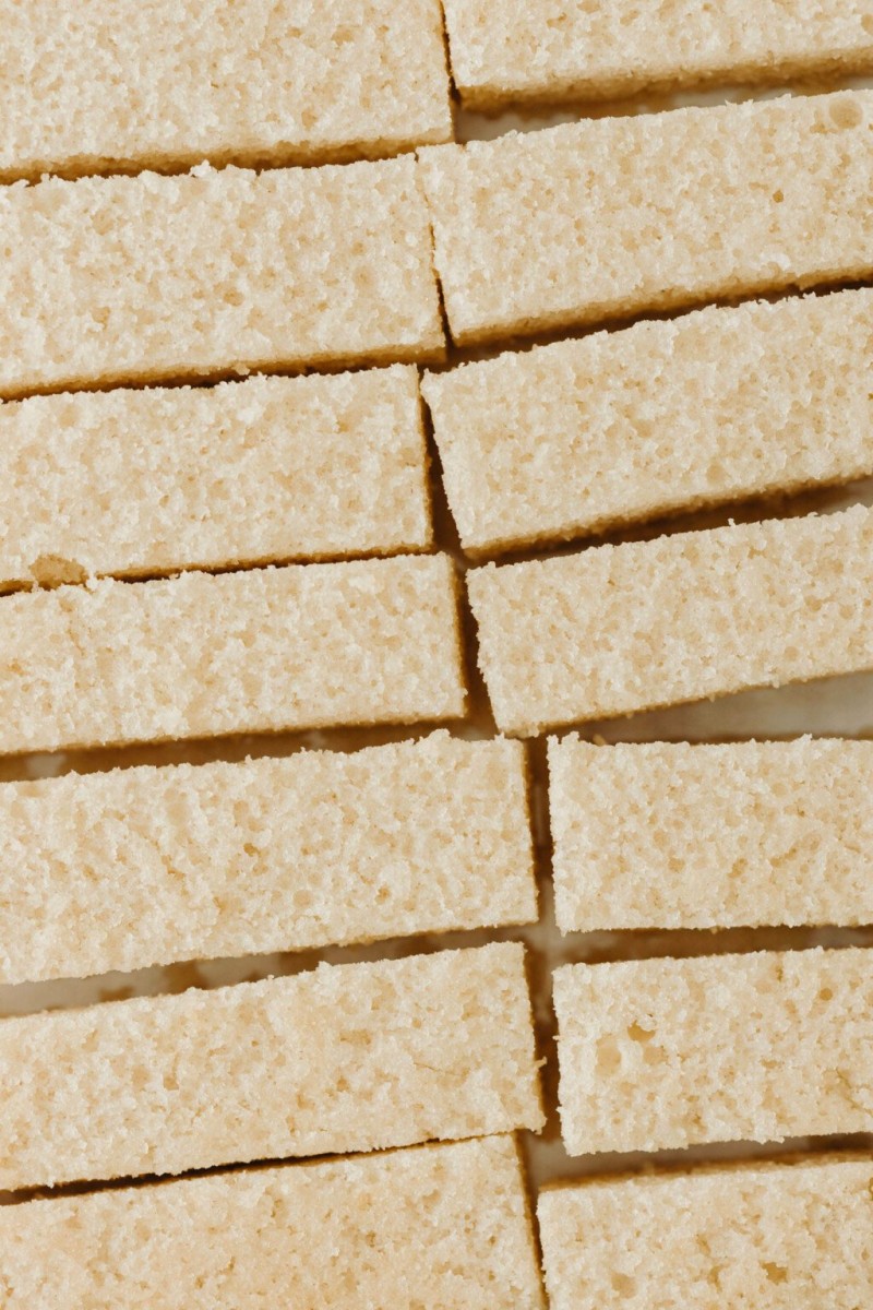 A baking sheet is covered with thin, rectangular slices of vanilla cake.