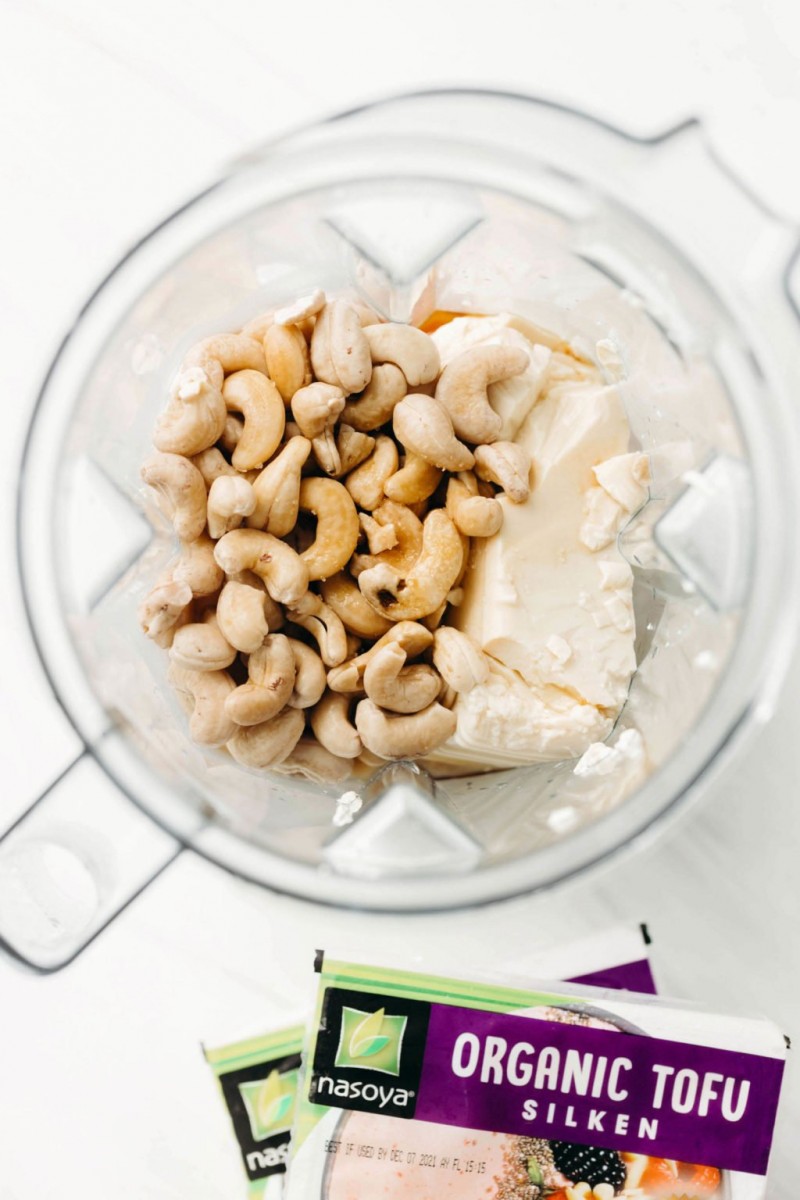 A blender is filled with a combination of raw cashews and silken tofu.