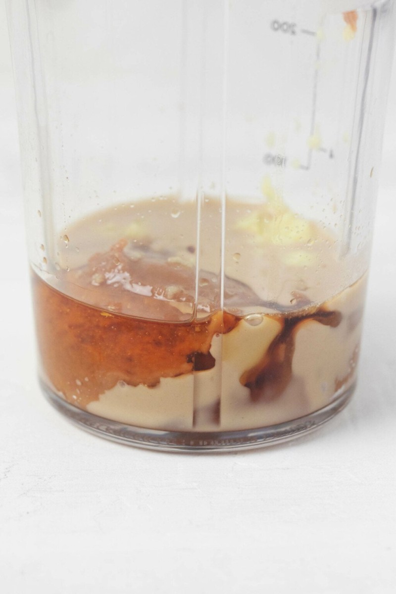 An image of tahini and maple syrup in the container of a portable blender.